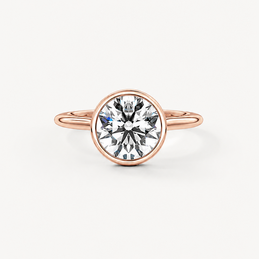 A rose gold ring with a round bezel setting holding a clear round-cut gemstone, shown against a plain off-white background.