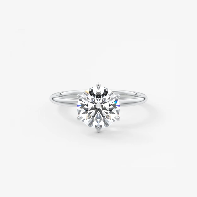 A classic solitaire engagement ring featuring a round brilliant-cut diamond set in a polished silver-colored band, centered on a clean white background.